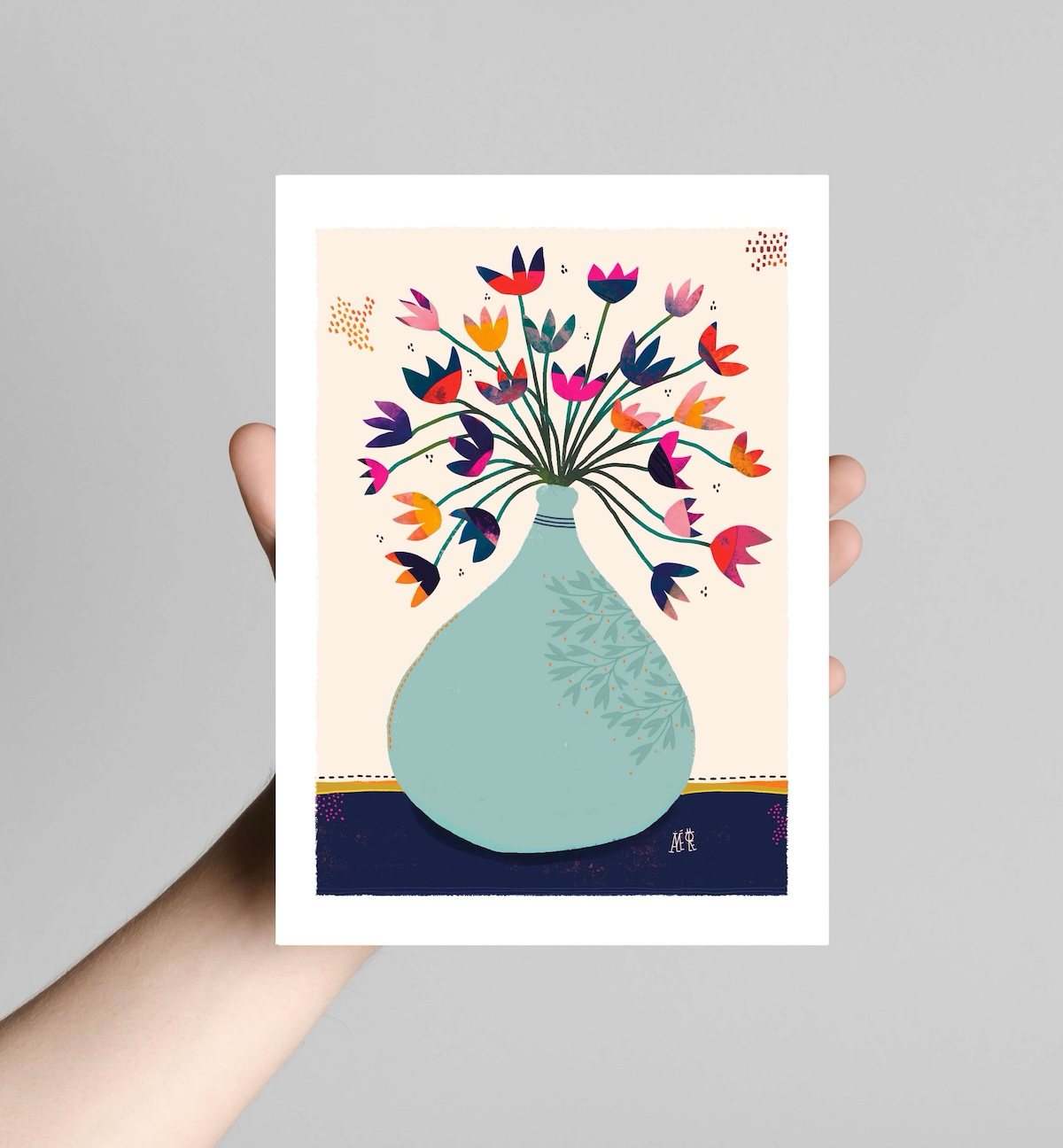 Bouquet de fleurs de forme à trois dents. Multicolores. Le vase est en forme des vase dame-jeanne. Bleu claire posé sur une nappe bleue marine. Idéale pour une décoration d'un bureau ou un cadeau anniversaire adulte
