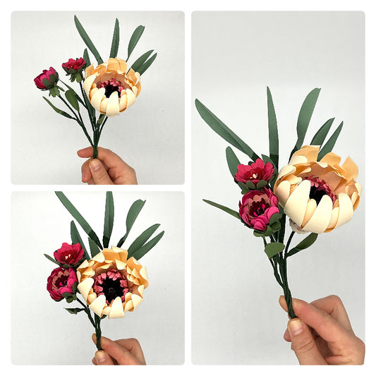 Photo d'un bouquet de fleurs en papier : une petite fleur ivoire, deux petites et du feuillage