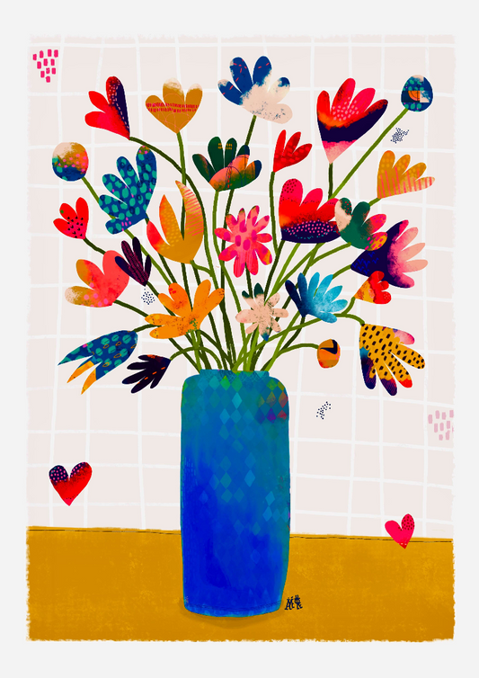 Bouquet de fleurs multicolores de formes variées. Le vase est long rectangulaire et bleu. Le vase est posé sur une nappe ocre.